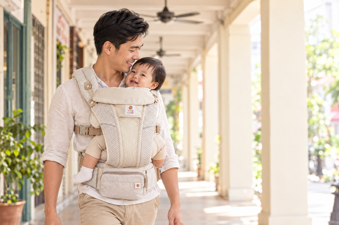 Dad wearing a baby facing inward in a breathable mesh TatoSnug baby carrier in a shophouse walkway under ceiling fans