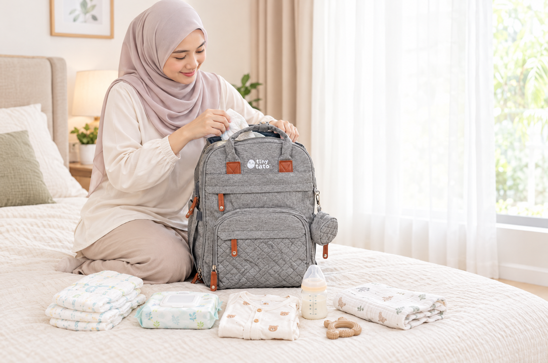 Ibu bertudung mengemas beg galas lampin TatoNest dengan lampin, tisu basah, baju dan botol susu di atas katil