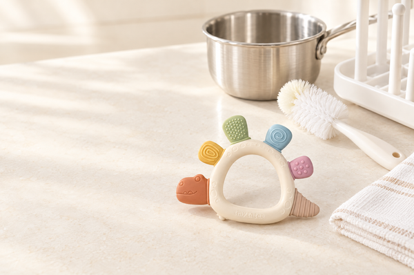 TatoChew silicone teether next to a pot, bottle brush and drying rack for cleaning and sterilising